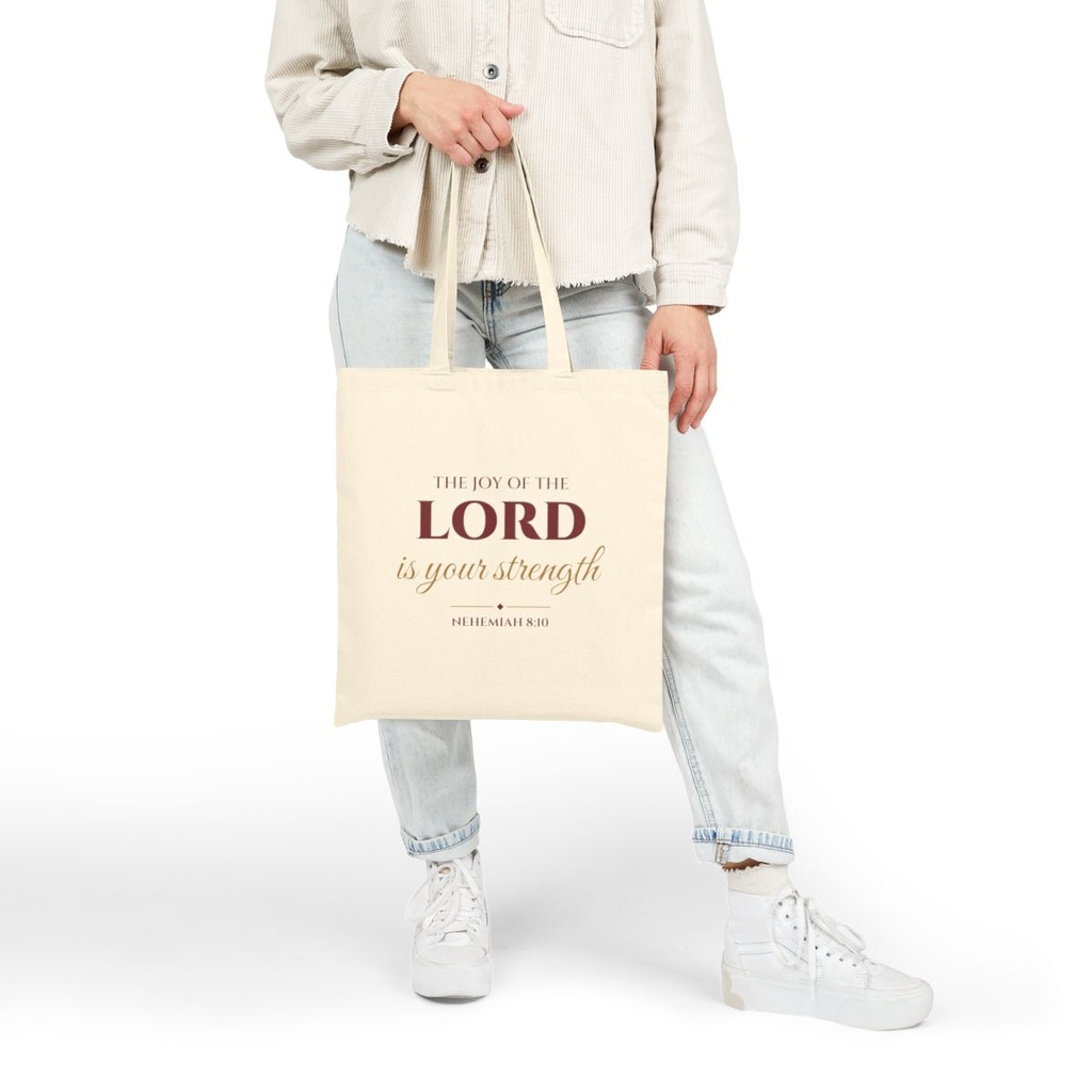 Joy of the Lord Christian canvas tote bag held by hand